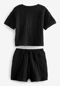Sort tekstureret co-ord sæt bestående af en kortærmet top og shorts med elastisk talje, begge lavet af krøllet stof med et åndbart design.