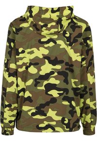 Kamouflagejacka med huva. Har en kombination av bruna, gröna och gula mönster, tillverkad av ett lent, lätt material.