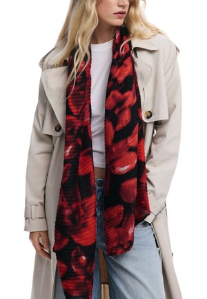 Sciarpa rossa e nera con motivo floreale, texture a coste e tessuto leggero, abbinata a un trench coat beige e una camicia bianca.