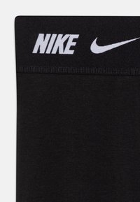 Black athletic leggings with a smooth texture, featuring a wide waistband displaying white "NIKE" logo and swoosh emblem.