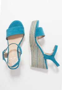 Tyrkysové semišové sandály na platformě s širokým předním popruhem, kotníkovým popruhem a tvarovanou tkanou mezipodrážkou. Jsou vybaveny gumovou podrážkou pro lepší přilnavost.