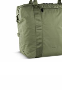 Olijfgroene nylon tote bag met dubbele handvatten, textuur oppervlak en een voorste ritszak. Heeft minimale branding en een rechthoekige vorm.