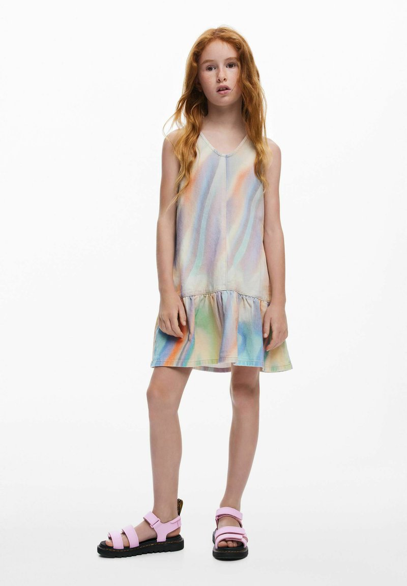 Robe pastel sans manches avec un ourlet à volants; présente un dégradé doux et multicolore. Associée à des sandales roses avec semelles noires.