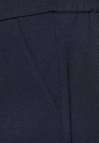 Navy-blaues Gewebe mit strukturiertem Finish, das über eine V-förmige Nahtdetails verfügt. Das Material wirkt weich und leicht.