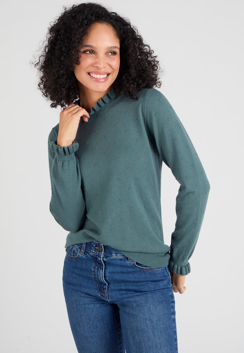 Teal gebreide trui met ronde halslijn en gerimpelde afwerking. Gestructureerd patroon van kleine lussen en strak aansluitende mouwen. Gedragen met denim jeans.
