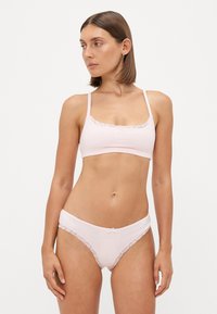 Light pink lingerie set featuring a bralette with lace trim and matching briefs, both made of soft fabric, designed for comfort.