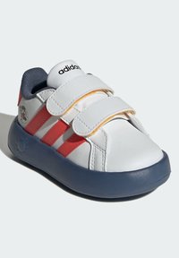 Białe syntetyczne buty z czerwonymi paskami i rzepami, zaokrąglony czubek, granatowe akcenty oraz logo w stylu kreskówkowym po boku.