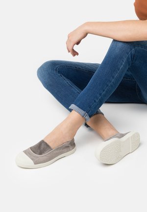 Sive slip-on cipele s nubuk gornjištem i gumenim vrhom. Potplat je bijel s teksturiranim uzorkom. Nosive s podvrnutim trapericama.