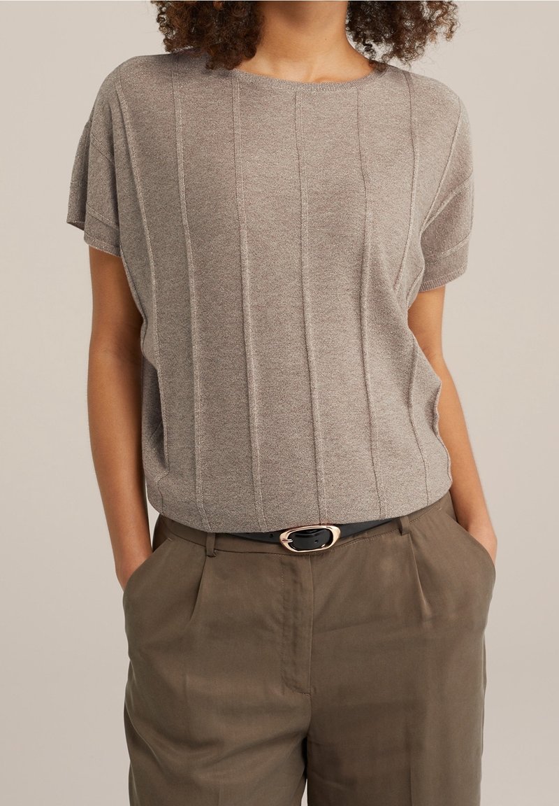 Beige stickad kortärmad topp med texturerade vertikala ränder, rund halsringning, i kombination med olivgröna byxor och ett svart bälte med ett guldspänne.