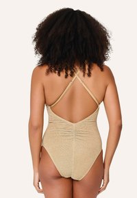 Zlatý, textúrovaný jednodielny plavky s nízkym zadočkom a krížovými ramienkami a bočným riasením pre priliehavý siluetu.