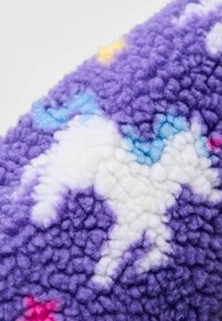 Tela de forro morada con textura suave, con un patrón de unicornios blancos acentuado por estrellas azules y amarillas. El diseño es caprichoso y colorido.