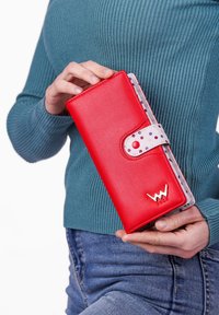Red faux leather wallet with a snap closure, white interior featuring colorful dots, and metal logo accent on the front.