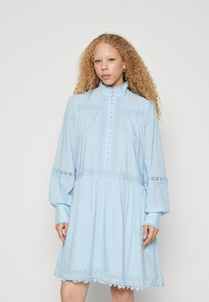 Abito di cotone azzurro chiaro con maniche lunghe, colletto alto, chiusura con bottoni, bordi in pizzo e dettagli in broderie anglaise sul corpetto e sulle maniche.