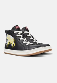 Svarte høyhælte sneakers med hvite lisser og såler, med et gult og hvitt tigerdesign på siden og rød Camper-logo på tungen.