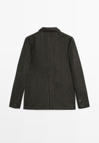 Blazer gris foncé, tissu texturé avec un motif subtil, col à revers cranté, fente arrière unique et poignets boutonnés. Design épuré et ajusté.