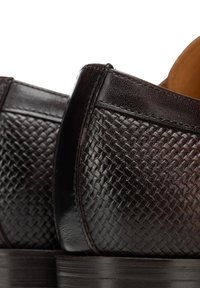 Chaussures en cuir brun foncé avec une texture tissée sur le côté, une finition lisse et une semelle noire robuste.
