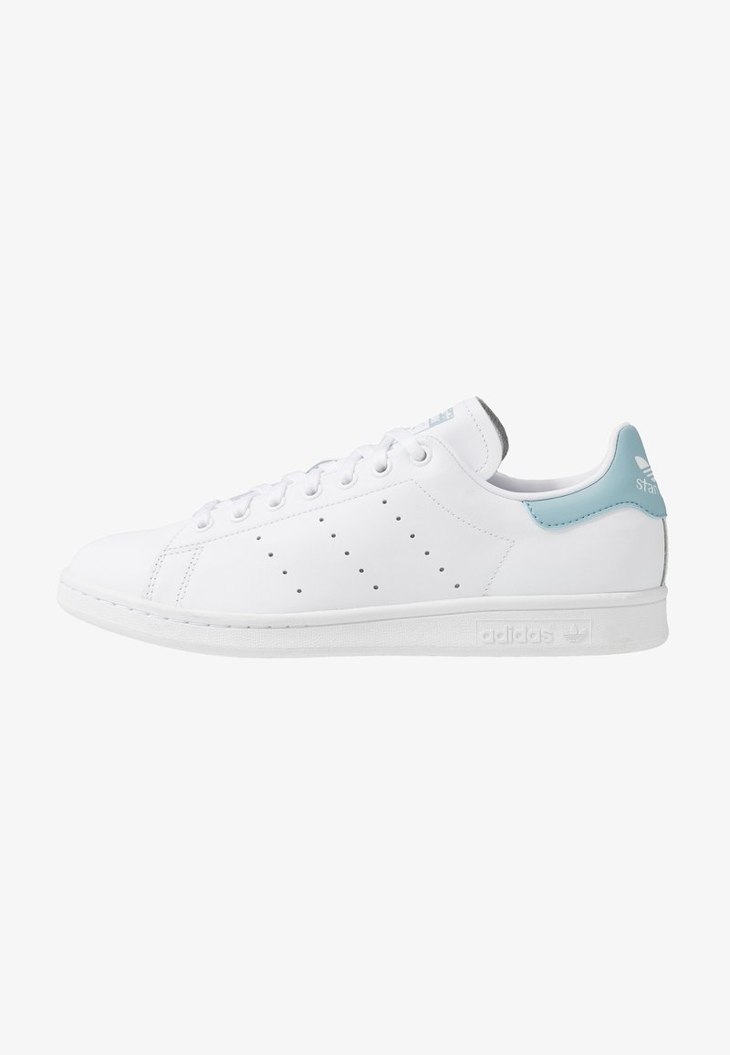 Baskets en cuir blanc avec une texture lisse, présentant un accent bleu clair au talon et de petites perforations sur les côtés. Semelle blanche simple.