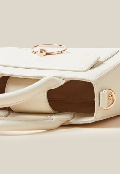Sac à main en cuir blanc avec un accent en anneau doré et une fermeture à rabat. L'intérieur est beige avec un design minimaliste, mettant en valeur une texture douce et des lignes épurées.