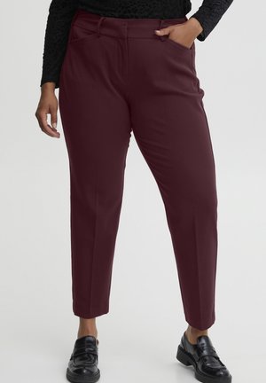 Pantalons bordeaux effilés en tissu lisse, avec des poches avant et une taille plate, assortis à des mocassins noirs.