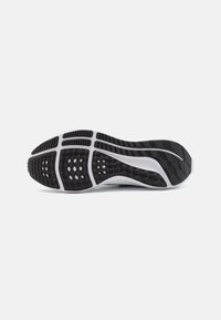 Suola di una scarpa con un design a onde; presenta motivi a diamante e esagonali; prevalentemente nera con accenti bianchi; materiale in gomma.