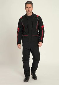 Schwarzer Motorradanzug mit roten Akzenten, ausgestattet mit einem Reißverschluss vorne, mehreren Taschen und strukturierten Paneelen an den Ellbogen und Knien.