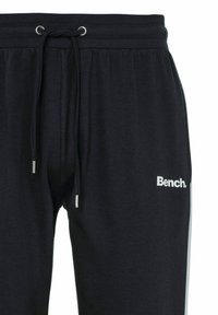 Schwarze Jogginghosen aus weichem Stoff, mit einem Kordelzugbund, silbernen Akzenten und einem weißen "Bench."-Logo am linken Oberschenkel.