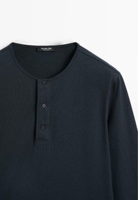 Dunkelblaues Langarm-Henley-Shirt mit drei Knöpfen und Rundhals-Ausschnitt, flach auf einem weißen Hintergrund ausgelegt.