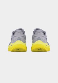 Ζεύγος γκρι και κίτρινων αθλητικών παπουτσιών που βλέπουν από πίσω σε λευκό φόντο, παρουσιάζοντας μαλακές σόλες και λεπτομέρειες λογότυπου της μάρκας.