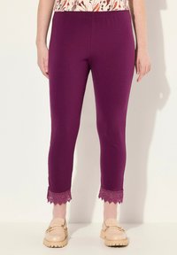 Leggings violets avec une taille élastique présentent des bordures en dentelle aux chevilles, fabriqués à partir d'un matériau doux, associés à des chaussures beiges à enfiler.