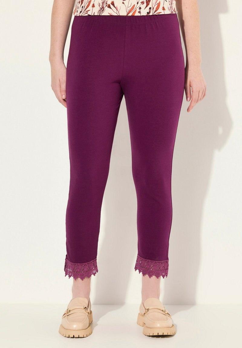 Leggings violets avec une taille élastique présentent des bordures en dentelle aux chevilles, fabriqués à partir d'un matériau doux, associés à des chaussures beiges à enfiler.