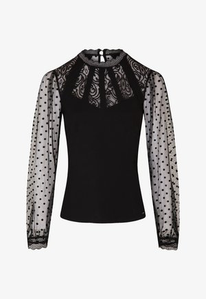 Zwarte top met een kant yoke en sheer mouwen met polkadots. De mouwen hebben een gegolfde rand, wat textuur en een decoratief element toevoegt.