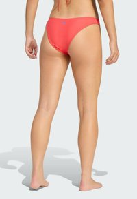 Różowe majtki bikini o niskim stanie, z niebieskim detalem logo. Gładka tekstura i minimalistyczny krój, odpowiednie do kostiumu kąpielowego.