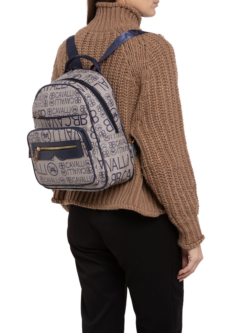 Zaino caratterizzato da un tessuto testurizzato con un motivo logo ripetuto in blu navy e beige, doppi scomparti con zip e spallacci regolabili.