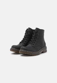 Stivali ankle in pelle nera con punta tonda, design con lacci, cuciture rinforzate e suola in gomma testurizzata. Presentano un dettaglio del logo sul lato.