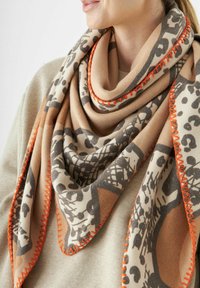 Écharpe beige avec un motif léopard en marron foncé et des coutures orange le long des bords. Tissu doux avec une forme triangulaire.