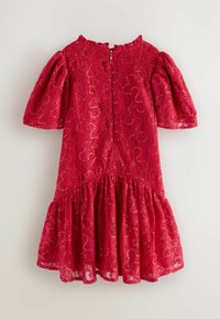 Czerwona koronkowa sukienka z bufiastymi krótkimi rękawami, falbaniastym wykończeniem dołu oraz zamek błyskawiczny z tyłu, ozdobiona rozrzuconymi cekinami dla nadania tekstury.