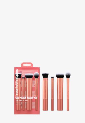 Fire sminkekoster i roségull med svarte og hvite børster, arrangert ved siden av matchende rosa emballasje med merkeetikett "Face Base Set."