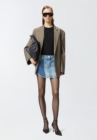 Preveliki bež blejzer, crni top, traper mini suknja s različitim teksturama, crna torba, prozirne crne čarape i špicasti crni visoki potpetice.