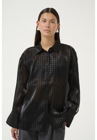 Sort, gennemsigtig skjorte med knapper og houndstooth-mønster, lange ærmer og klassisk krave. Materialet har en glat, let glansfuld tekstur.