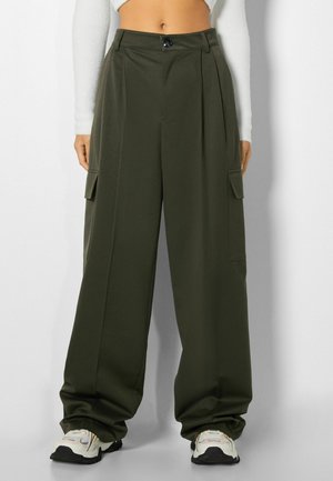 Pantalons cargo olive à taille haute, larges avec des plis sur le devant, poches latérales et fermeture à bouton. Fabriqués dans un tissu lisse.