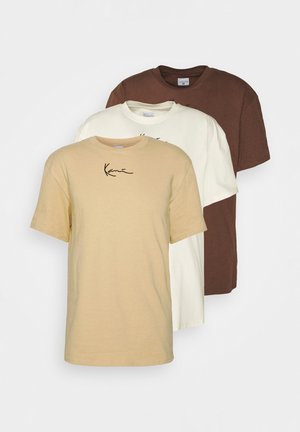 Drie effen T-shirts met korte mouwen in beige, wit en bruin met kleine zwarte handtekeningtekst op de voorkant bij het borstgebied.