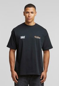 Svart bomull T-skjorte med rund hals. Har hvit tekst "out of office" og gullbroderi med "Off Season" på venstre bryst.