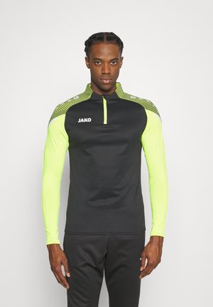 Sportshirt met lange mouwen, zwart met neongele mouwen. Voorzien van een ritssluiting bij de kraag en een groen patroon op de schouders.
