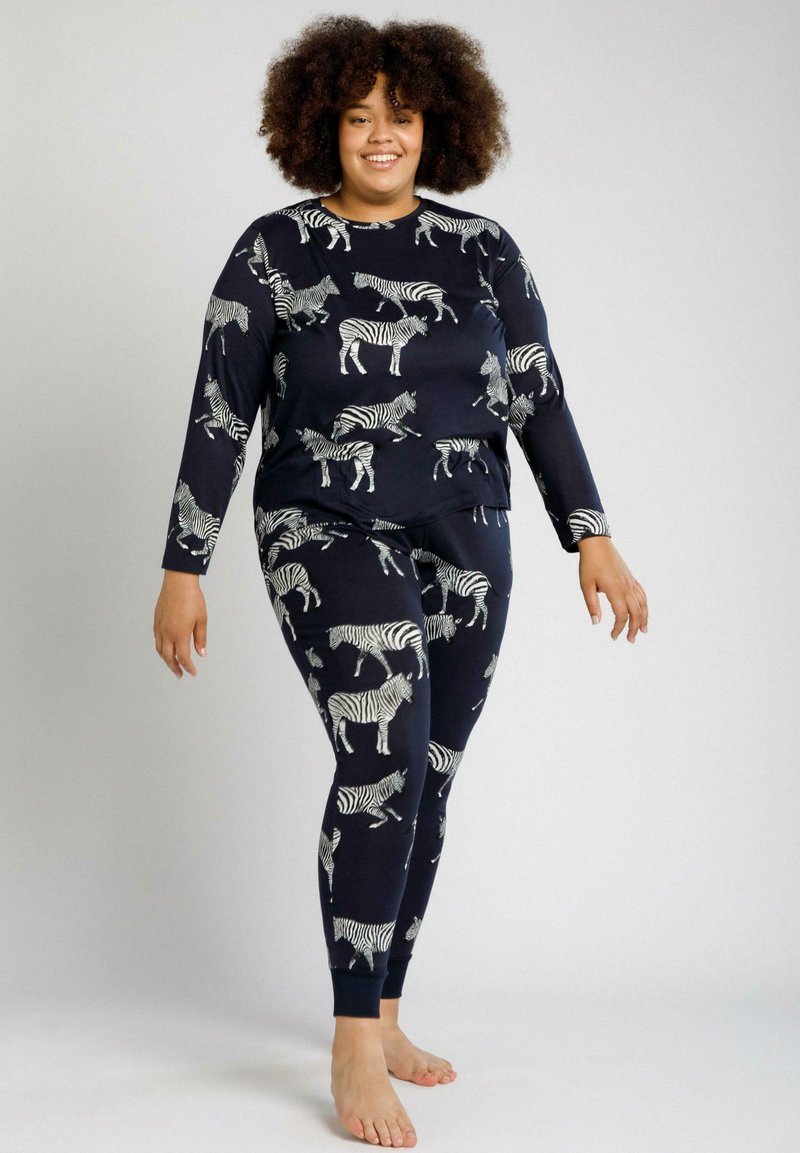 Conjunto de loungewear en color marino que incluye una camiseta de manga larga y leggings con un patrón de cebra blanco. Material suave con puños y cinturilla acanalados.