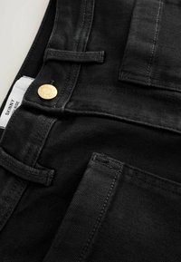 Černé skinny džíny s zlatým knoflíkem, viditelným prošitím a poutky na opasek. Vyrobeny z denimu s hladkou texturou a přiléhavým střihem.