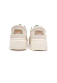 Light beige suede sneakers with a textured back, green and blue accent stitching, and a thick white rubber sole. Embossed brand label on heel.