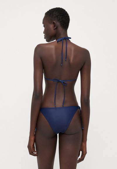 Tamsiai mėlynos spalvos bikini rinkinys su kaklo virvute ir reguliuojamais šoninėmis raišteliais. Sklandžią tekstūrą turintis minimalizmo stiliaus kostiumas, tinkantis maudymosi drabužiams.
