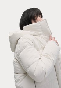 Puffy witte jas met een hoge kraag en capuchon, voorzien van gestikte delen, een gladde stofstructuur en een relaxed fit.