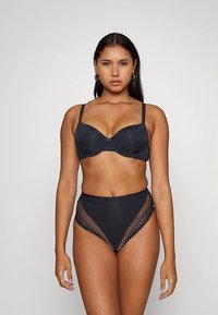 Conjunto de lencería negra que incluye un sujetador con relleno y acabado suave, y braguitas de talle alto, con detalles de encaje en los laterales.