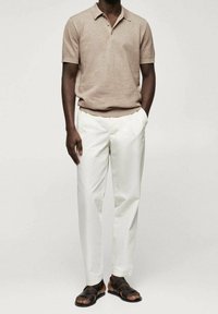 Polo shirt beige à manches courtes avec un col, associé à un pantalon blanc sur mesure et des sandales en cuir noires. Design simple, tissu respirant.